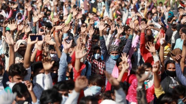 Migrant workers raise their hands as policemen ask them for their destination as they wait for buses along a highway with their families as they return to their villages, during a 21-day nationwide lockdown to limit the spreading of coronavirus disease (COVID-19), in Ghaziabad, on the outskirts of New Delhi, India, 28 March 2020.
