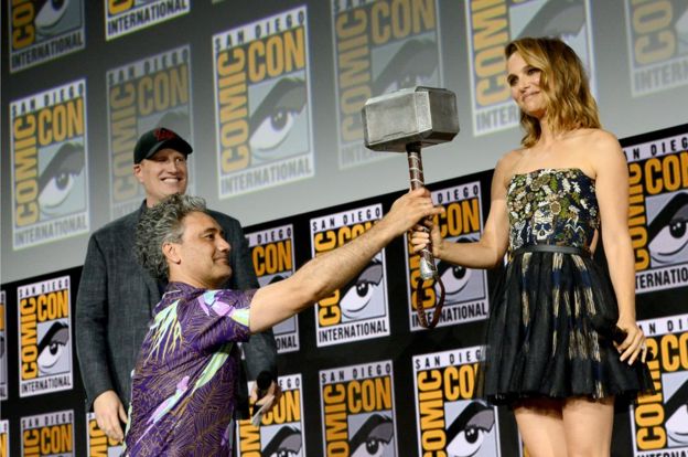 Natalie Portman holding a hammer which has just been handed to her.