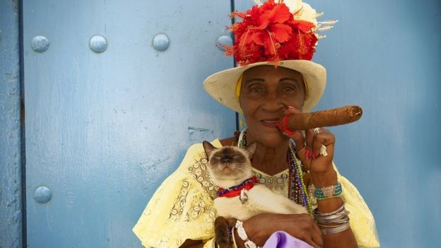 A woman with a cat in her arms and smoking a cigar in Cuba