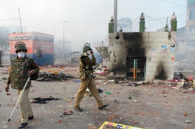 Policemen stand on a vandalised road following clashes between supporters and opponents of a new citizenship law, at Bhajanpura area of New Delhi on February 24, 2020, ahead of US President arrival in New Delhi.