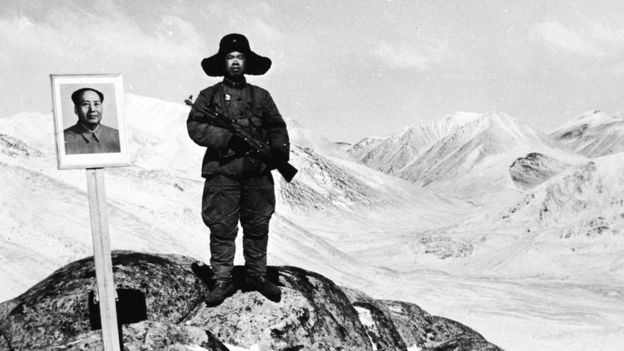 Un guardia fronterizo junto a un retrato de Mao Zedong.