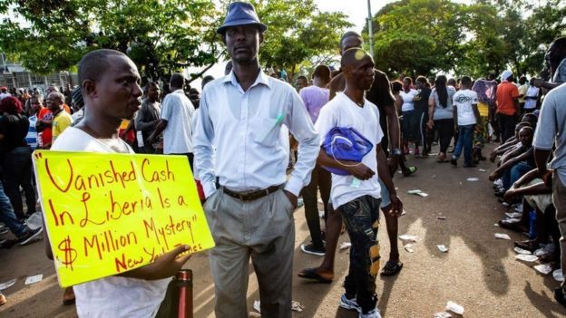 A many holds up a sign quoting an article about millions of dollars that disappeared shortly after arrival from abroad during an anti-government demonstration, on June 7, 2019, in Monrovia.