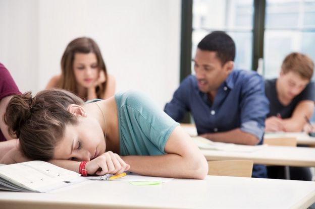 Una adolescente dormida en un salón de clases.