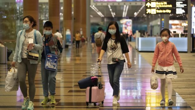 Família com máscaras caminha em saguão de aeroportos
