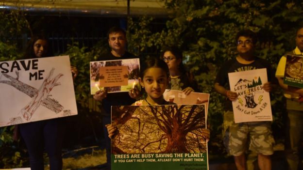 Residents hold placards and light candles to protest against the cutting of more than 16,000 trees