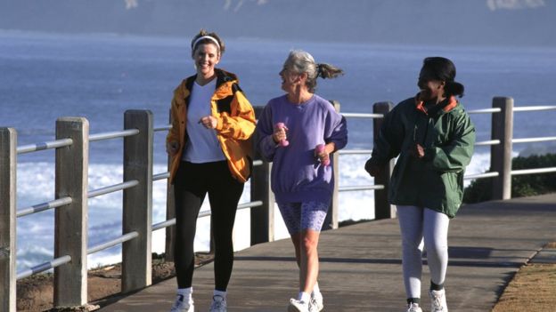 Tres mujeres andando con ritmo rÃ¡pido por un embarcadero.