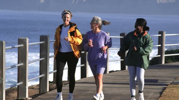 Tres mujeres andando con ritmo rápido por un embarcadero.  Qué tipo de deporte es mejor para estar sano según tu edad  105556394 correr