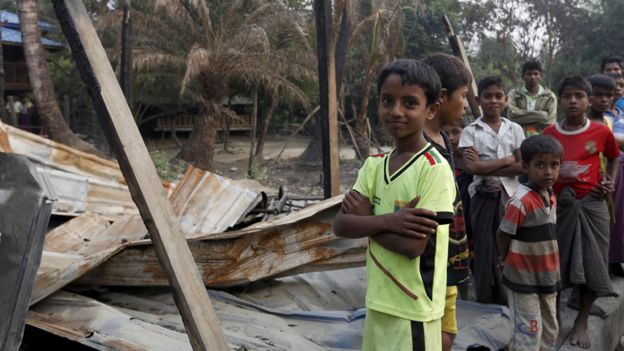 Niños rohingya frente a una casa destruida