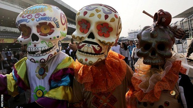 Giant figures depicting skulls take part in a performance before practice