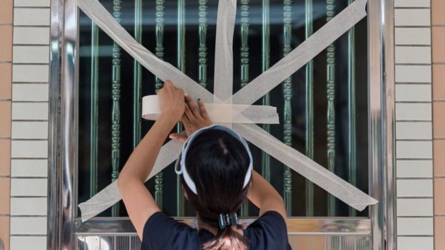 A resident of a fishing village in Hong Kong tapes up her windows