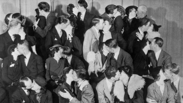 Foto en blanco y negro de muchas parejas besándose