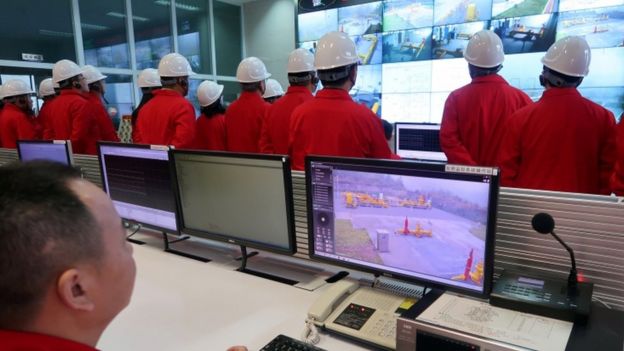 Imagem mostra funcionários da PetroChina em uma sala com diversas telas onde são exibidas etapas da produção