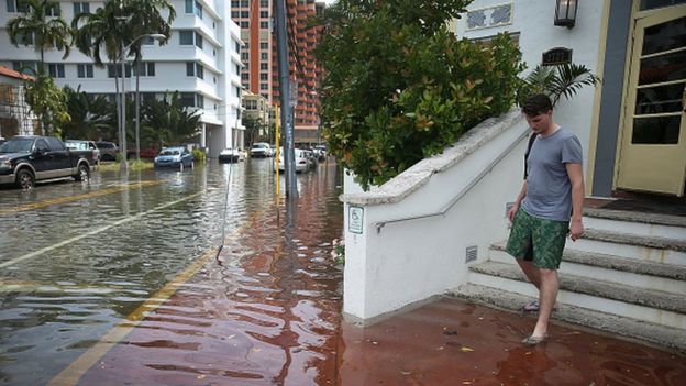 Hombre saliendo de un edificio en una calle inundada