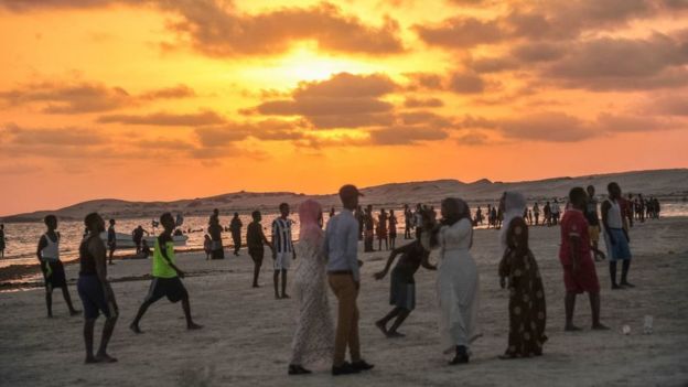 Somalians walk along a beach outside Mogadishu at sunset