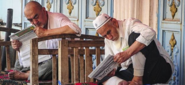 Warga Uighur membaca koran