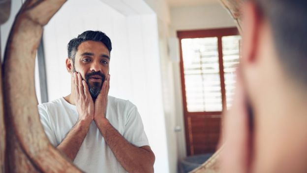 Hombre de mediana edad mirándose al espejo.