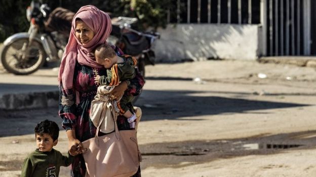 A Syrian woman and children fleeing the battle zone between Turkey-led forces and Kurdish fighters
