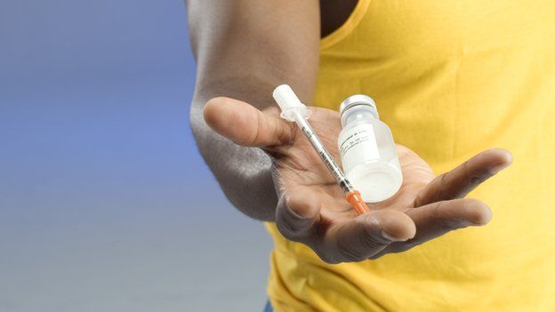 An athlete holds a syringe and medicine bottle
