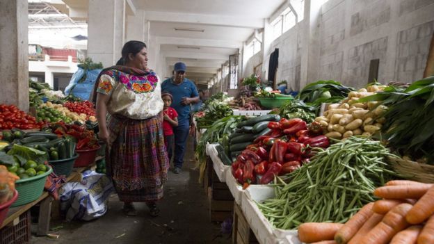 Una familia compra verduras en un mercado en Zunil