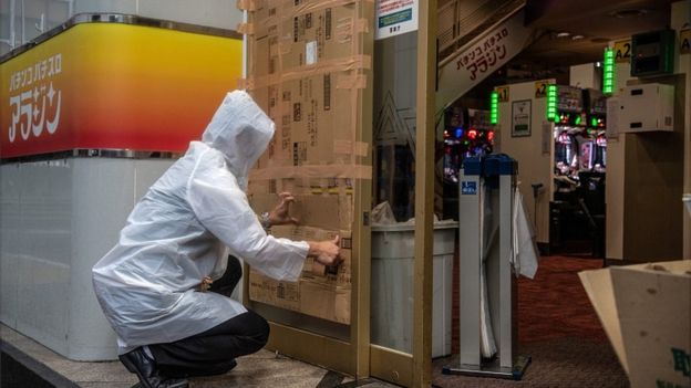 A man covers over a doorway to a pachinko parlour ahead of the arrival of Typhoon Hagibis on October 12, 2019 in Tokyo, Japan