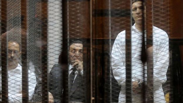 مبارك يجلس بين ابنيه علاء، على اليمين، وجمال خلال محاكمتهم في قضية فساد