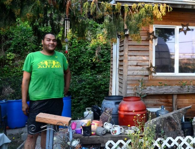 Um homem apelidado de Tequila diante da casa em que vive em um acampamento para pessoas sem teto em Portland, nos EUA