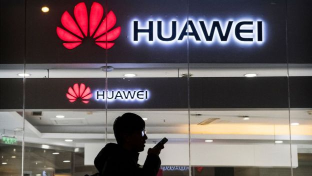 Un hombre habla por un teléfono frente a una tienda Huawei.
