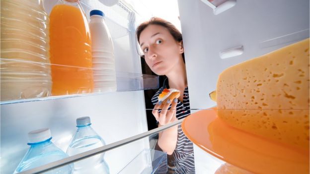 Mujer mirando dentro de un refrigerador