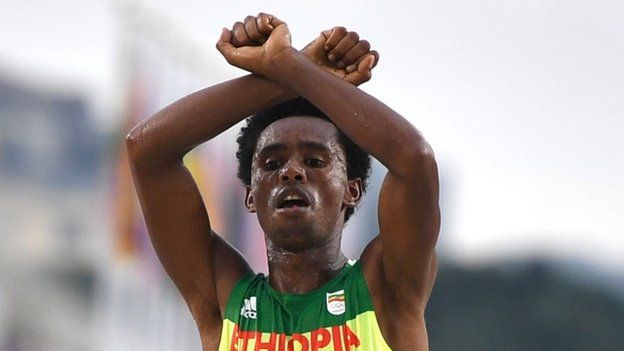 Ethiopia's Feyisa Lilesa crossed his arms above his head at the finish line of the Men"s Marathon athletics event of the Rio 2016 Olympic Games at the Sambodromo in Rio de Janeiro on August 21, 2016.