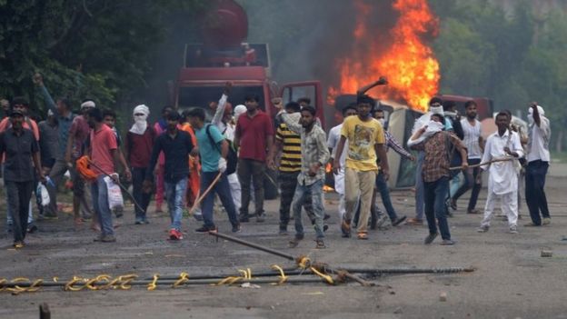 Supporters of Indian religious leader Gurmeet Ram Rahim Singh throw stones at security forces next to burning vehicles during clashes in Panchkula on August 25, 2017.
