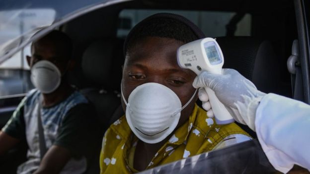 Un miembro del personal del Ministerio de Salud le mide la temperatura a los conductores en una carretera en Kenia.