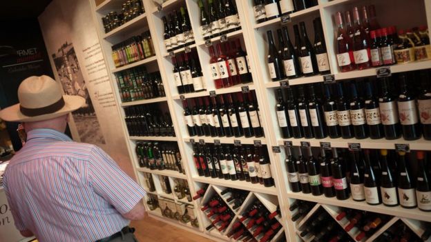 An elderly man looks at bottles of wine displayed inside a store