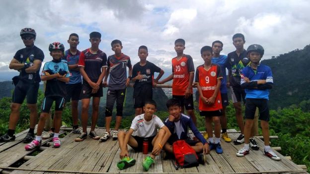 Meninos posam para foto com o treinador de futebol