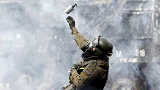 Un militar lanza un cartucho de gas lacrimógeno