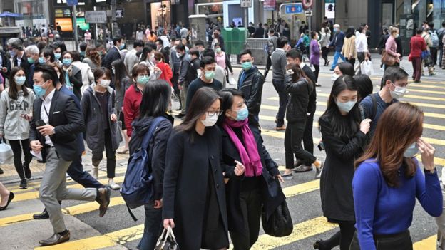 Pedestrians wear face masks, as a precautionary measure against the COVID-19 coronavirus, in Hong Kong on March 12, 2020