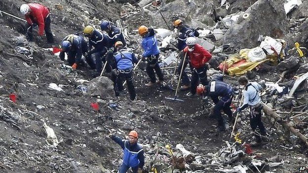 Rescue workers work on debris of the Germanwings jet at the crash site