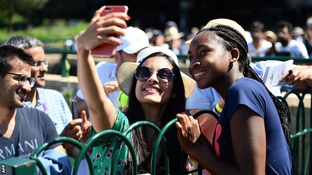 Coco Gauff poses with a fan for a picture
