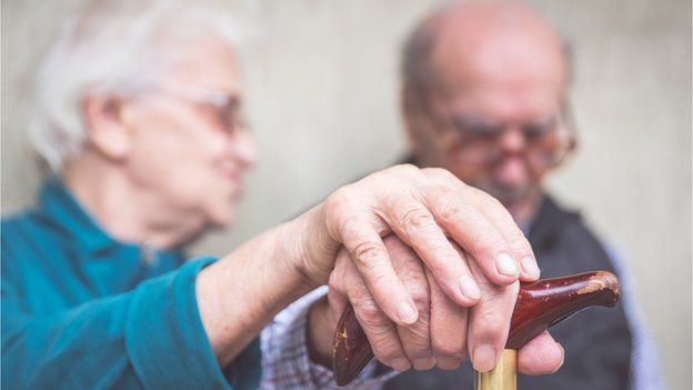 elderly couple holding hands