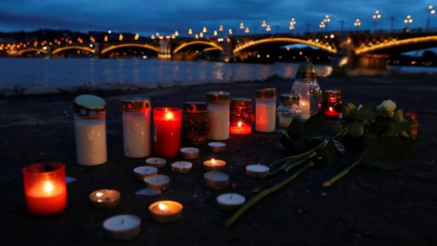 Candles burn at the river's bank near the site of a ship accident,