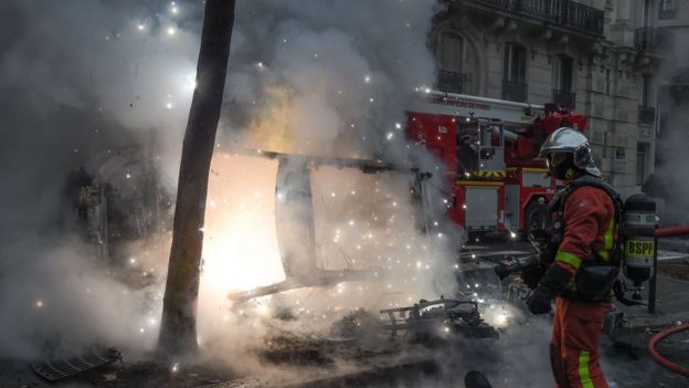 A fireman stands next to a vehicle set on fire by protesters during Paris riots, 8 December 2018