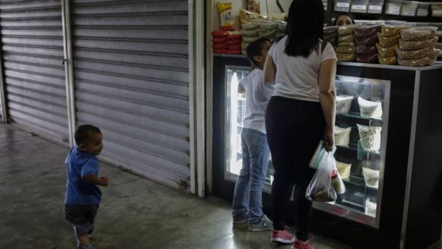 Mulher compra alimentos na Venezuela