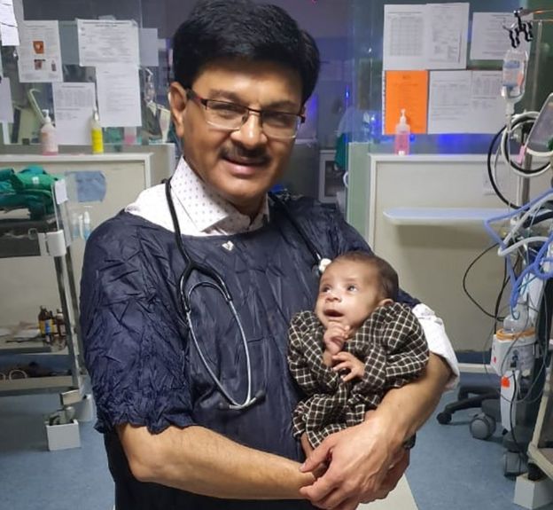 O pediatra Ravi Khanna com a menina nos braços