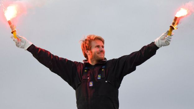 French sailor Francois Gabart celebrates aboard his trimaran Macif upon his arrival at the end of his solo around the world navigation, on December 17, 2017 in Brest, western France