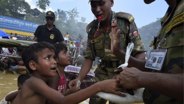 Bangladeshi soldiers distribute rice to young Rohingya refugees at the camp of Balukhali near Gumdhum on September 25, 2017