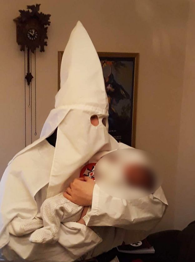 Adam Thomas usa roupa da KKK enquanto segura seu filho no colo