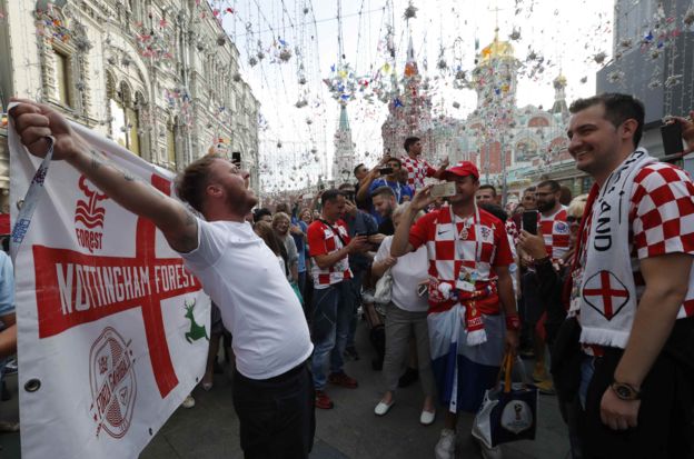 An England supporter cheers next to Croatia fans before the match in the city centre