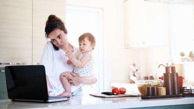 Mãe trabalhando com bebê no colo