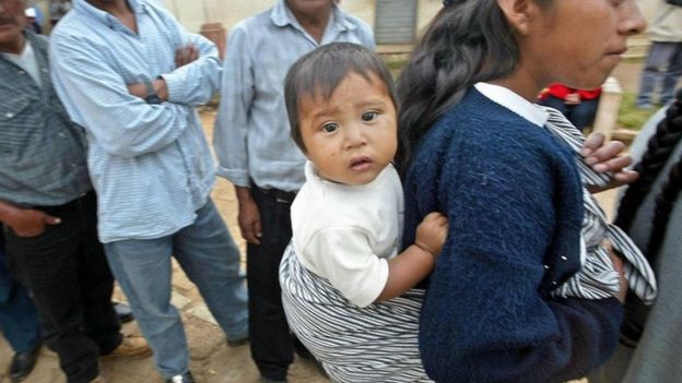 Una joven con un bebé en su espalda