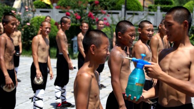 Murid perguruan bela diri di Zhengshou, Provinsi Henan, China, menghindari sengatan panas matahari dengan menyemprotkan air ke muka