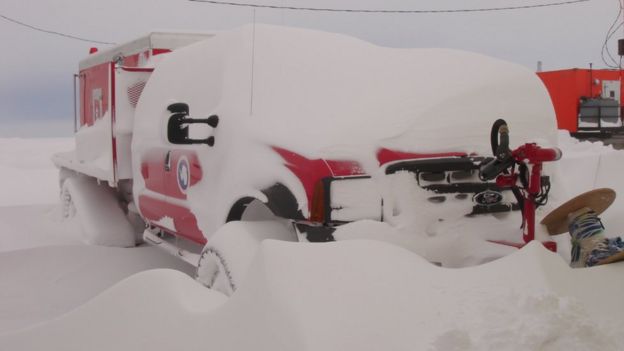 An emergency vehicle partially covered in snow